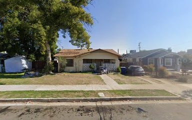 Fresno, CA home bought by Varo as-is: stucco bungalow with a tile roof and a front lawn